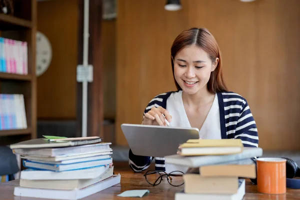 stock image Young asian woman student working on digital tablet in library