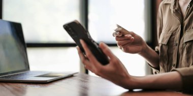 Kredi kartı ve akıllı telefonu tutan kadınların ellerini kapat. İnternetten ödeme yapan genç bir kadın. Bankacılık hizmetini kullanan, bilgi giren, alışveriş yapan, internet mağazasından sipariş veren, güvenli ödeme yapan bir kadın..