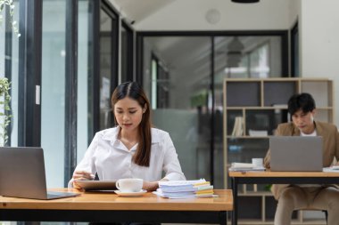 İş arkadaşlarıyla dijital tablet kullanan genç bir iş kadını. Ofisteki finansal ve pazarlama projeleri üzerinde çalışıyorum.