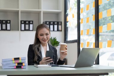 Beautiful young business woman using phone in office.