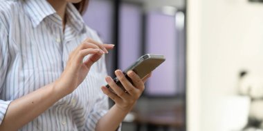 Güzel bir Asyalı kadın cep telefonu tutuyor ve kullanıyor.