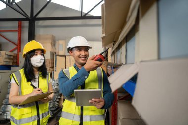 Üniformalı iki güler yüzlü depo çalışanı ve sarı başlıklı adamlar ayakta iş hakkında konuşuyorlar. danışman