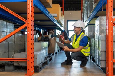 Male dispatcher checking packages while using walkie-talkie in distribution warehouse