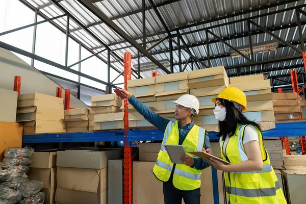 stock image Two smile warehouse workers in uniforms and yellow helmets on heads standing and talking about job. adviser