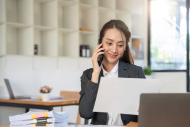 İş kadını akıllı telefonu ofis, vergi, muhasebe, finansal konsebe, ahşap masa üzerinde matematik finansmanı için kullanıyor..
