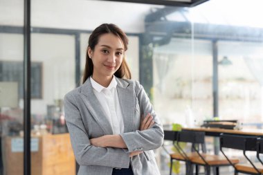 Asyalı, gri takım elbiseli, gülümseyen, kameraya güvenle bakan bir portre..