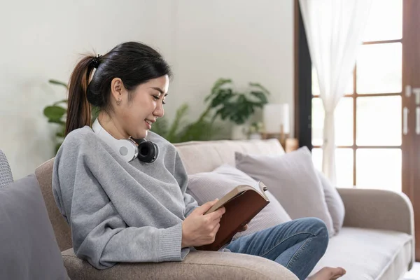 Junge Schöne Asiatische Studentin Sitzt Auf Sofa Und Liest Buch — Stockfoto