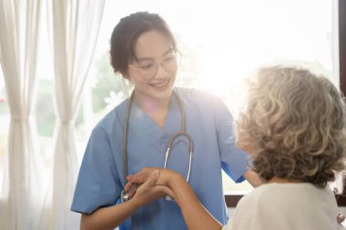 Genç bakıcı yaşlı kadına yardım ediyor. Hemşire yaşlı kadınına bakımevinde yardım ediyor..