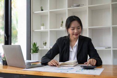 Hesap makinesi ve dizüstü bilgisayar kullanan iş kadını ofis ve iş geçmişinde, vergi, muhasebe, istatistik ve analitik araştırma kavramında ahşap masada finans yapıyor..