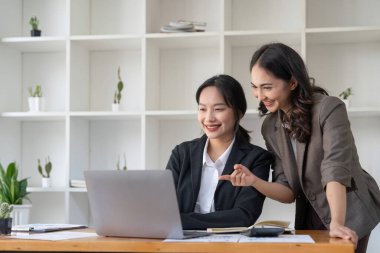 Young colleagues discuss business and analytical price charts using calculators and laptops to calculate financial, tax, accounting, statistics and analytical research ideas.
