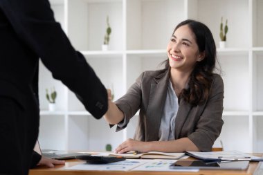 Smiling young businesswoman shaking hands with an office colleague.