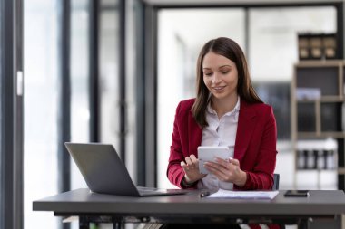 businesswoman using a calculator to check company finances and earnings and budget. Business woman calculating monthly expenses, managing budget, papers, loan documents, invoices.
