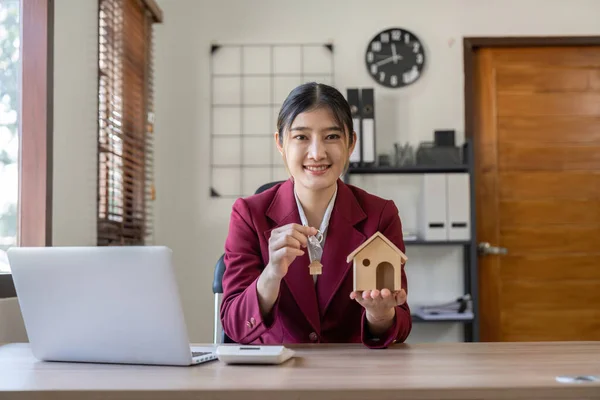 Real estate woman holding house model and house key in hand.Mortgage loan approval home loan and insurance concept