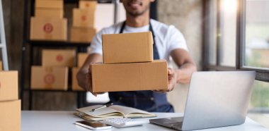 Küçük işletme sahibi iş yerindeki karton kutuya adres yazıyor. Küçük işletme girişimcisi KME, evdeki kutuyla çalışıyor, çevrimiçi satış, e-ticaret, paketleme konsepti.