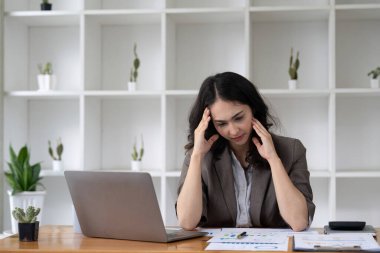 Yorgun ve Asyalı bir kadının portresi ofiste vergi bilgisayarıyla çalışıyor. Üzgün, mutsuz, endişeli, depresyon ya da çalışan hayatı stres konsepti.