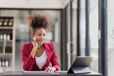 Female office worker working on a laptop in an office.