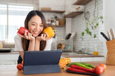 woman in the kitchen preparing materials ready to cook looking at recipes on tablet.