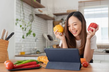 woman in the kitchen preparing materials ready to cook looking at recipes on tablet.