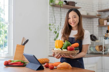woman in the kitchen preparing materials ready to cook looking at recipes on tablet.