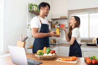 Happy couple preparing food together in kitchen at home ready to cook together.