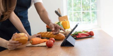Happy couple preparing food together in kitchen at home ready to cook together.