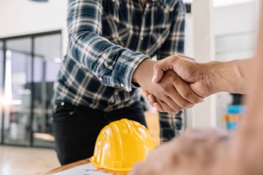 Architect and engineer construction workers shaking hands while working for teamwork and cooperation concept after finish an agreement in the office construction site.