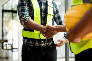 Architect and engineer construction workers shaking hands while working for teamwork and cooperation concept after finish an agreement in the office construction site.