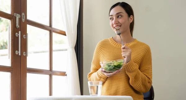 Delighted woman eating food for health at home.