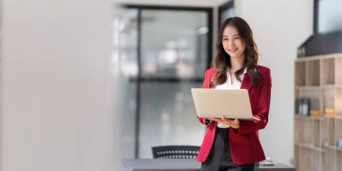 Young businesswoman working in the office while standing near window.