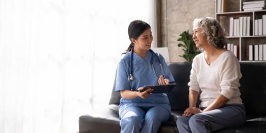 Smiling female doctor showing test results to patient in hospital. Sick senior woman having a doctor appointment. Medical consultation.