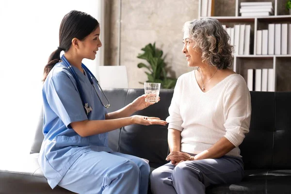 Healthcare worker or nurse caregiver giving pills, showing a prescription drug to senior woman. Elderly healthcare concept.