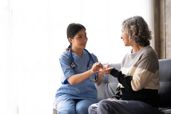Healthcare worker or nurse caregiver giving pills, showing a prescription drug to senior woman. Elderly healthcare concept.