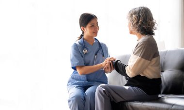 caregiver nurse holding hand of happy elderly woman.