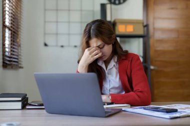 Tired young asian business woman with headache at office, feeling sick at work.