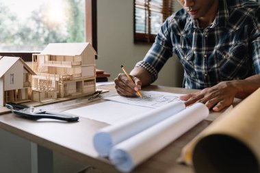 Concept architects, engineer or architect holding pen drawing on blueprint architectural. equipment architects On the desk with a blueprint in the office.