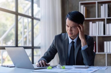 Stressed young asian businessman,Documents related to finance, tax ,push down calculator to calculate tax income and expenses, bills, office.Financial, finance concept.