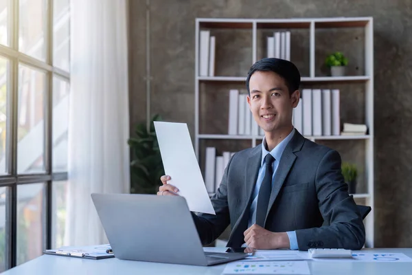 Busy businessman accountant Asian male making look document in office working, , report, tax, accounting, statistics, and analytic research concept.