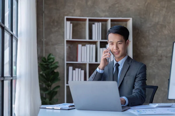 Busy businessman accountant Asian male making call phone in office working, Startup, report, tax, accounting, statistics, and analytic research concept.