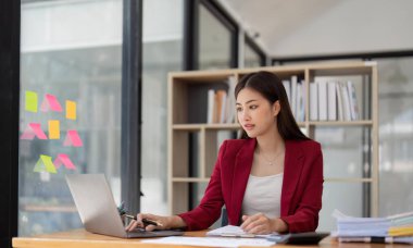 Bir ofis masası, vergi, rapor, muhasebe, istatistik ve analitik araştırma kavramında matematik finansmanı için hesap makinesi ve dizüstü bilgisayar kullanan Asyalı İş kadını.