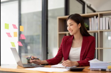 Bir ofis masası, vergi, rapor, muhasebe, istatistik ve analitik araştırma kavramında matematik finansmanı için hesap makinesi ve dizüstü bilgisayar kullanan Asyalı İş kadını.