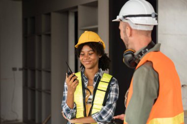 Kadın mühendisler ellerinde telsiz telsizi ve inşaat alanını inceliyor..