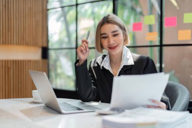 Muhasebe belgelerini tutan genç bir iş kadını ya da şirket çalışanı finansal verileri ya da pazarlama raporlarını kontrol ediyor. Belge yönetimi.