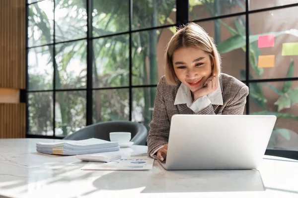 会計から書類をチェックする若いビジネスの女性は データベースをチェックするためにコンピュータのラップトップを使用して 文書上の番号を分析する — ストック写真