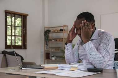 Ofiste oturan stresli bir iş adamı. Yorgun ve çok çalışan siyahi bir adam. Genç Afro-Amerikalı stresli adamlar dizüstü bilgisayarla çalışıyorlar..