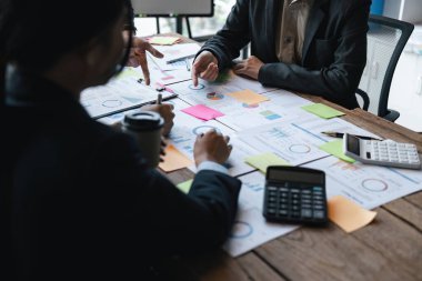 Bir grup iş adamı toplantı odasında şirket yatırım belgeleri konusunda mevcut finans ve ekonomiyi tartışıyor..