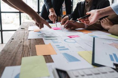 Bir grup iş adamı toplantı odasında şirket yatırım belgeleri konusunda mevcut finans ve ekonomiyi tartışıyor..