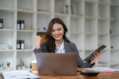 Mutlu kadın ofis çalışanı heyecan dolu yumruklar kariyer terfisini ya da ödülünü kutluyor, masa başında oturan iş kadını online haberler alıyor, harika sonuçlar alan başarılı iş kavramı.