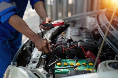 Kapatma teknisyeni, araba aküsündeki voltaj seviyesini kontrol etmek için multimetre voltmetre kullanıyor. Servis ve Bakım araba aküsü..