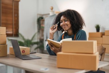 Girişimci, küçük işletme, KOBİ, yanında bir sürü kutuyla evden çalışan serbest çalışan kadın. Ticari izleme için akıllı telefonlar ve dizüstü bilgisayarlar kullanın. Çevrimiçi pazarlama paketleme kutusu satışı.