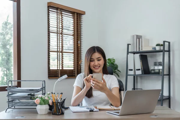 business woman with phone for communication, connection and typing while smile, happy and relax. Entrepreneur, excited and with laptop for planning at home.